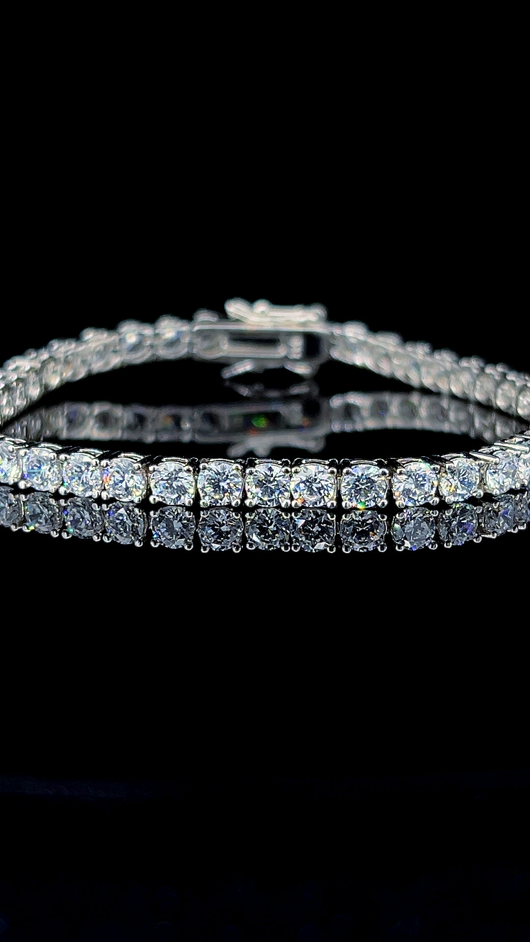 Classic 925 sterling silver tennis bracelet featuring round brilliant cubic zirconia stones on a dark reflective surface.